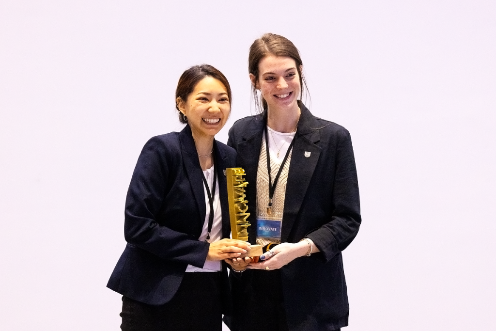 Two female students smile with an Innovate competition trophy.