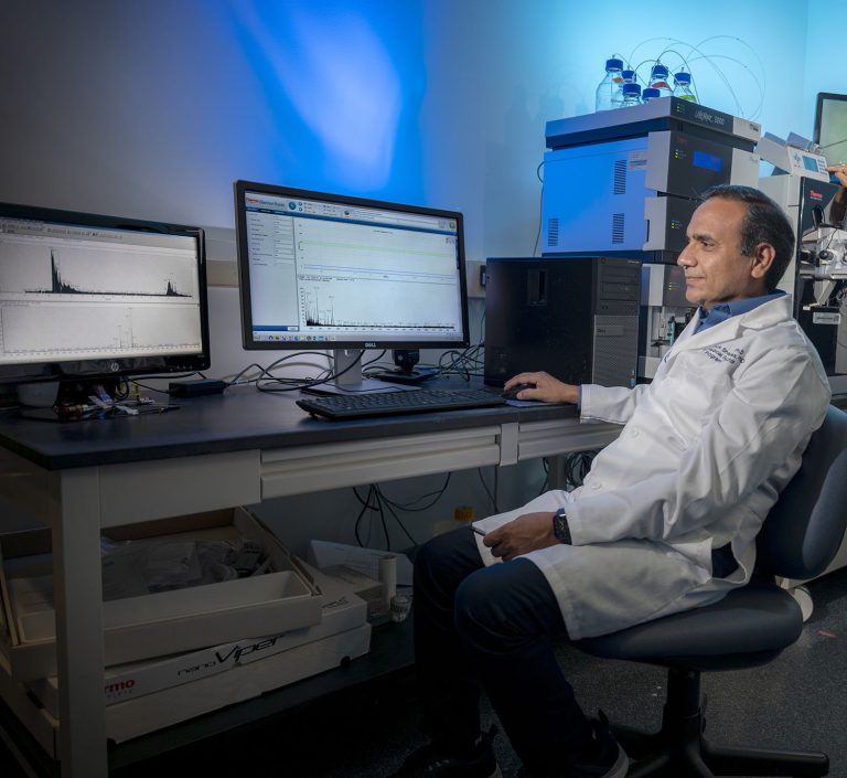 Man in white coat sits at computer