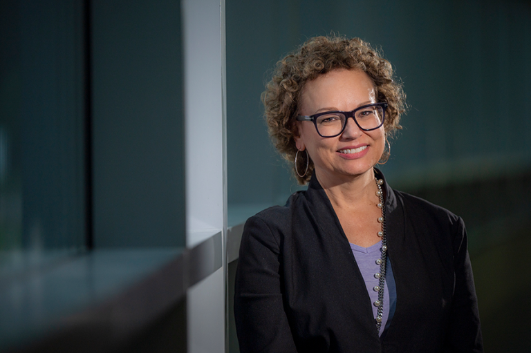 Woman wearing glasses smiles for a photo.