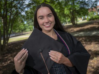 Woman smiling while holding cap for graduation