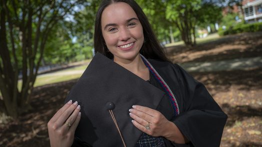 Woman smiling while holding cap for graduation