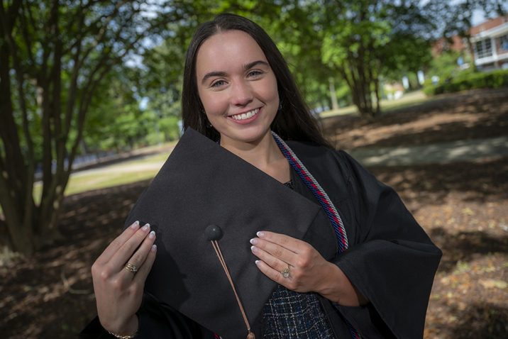 Woman smiling while holding cap for graduation