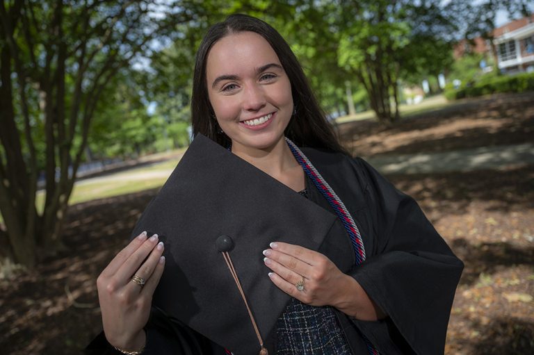 Woman smiling while holding cap for graduation