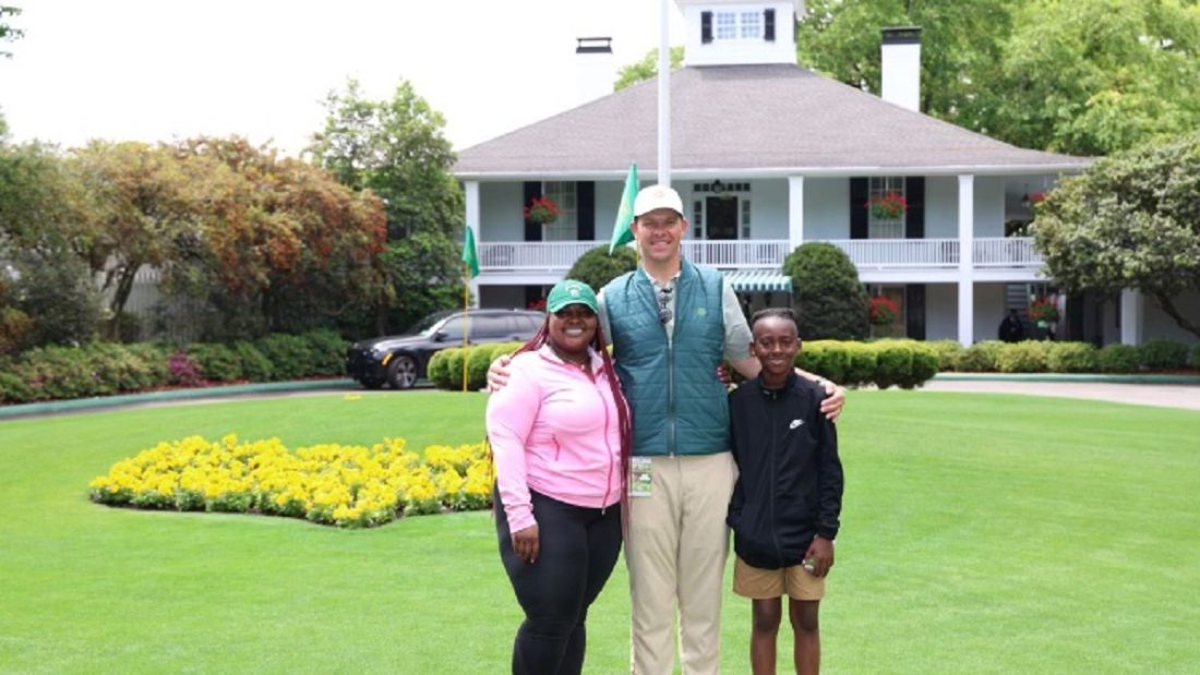 A man poses with a mom and her son outside the Augusta National Golf Club clubhouse.
