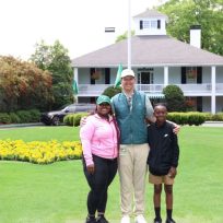 A man poses with a mom and her son outside the Augusta National Golf Club clubhouse.