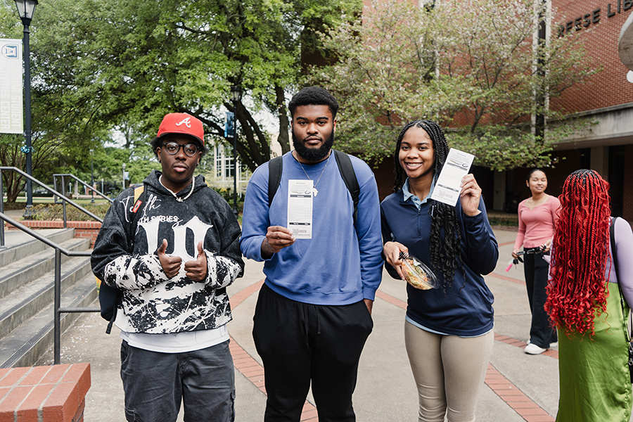 Three college students hold up information packets about driving impaired during a recent Arrive Alive Tour stop on a college campus.