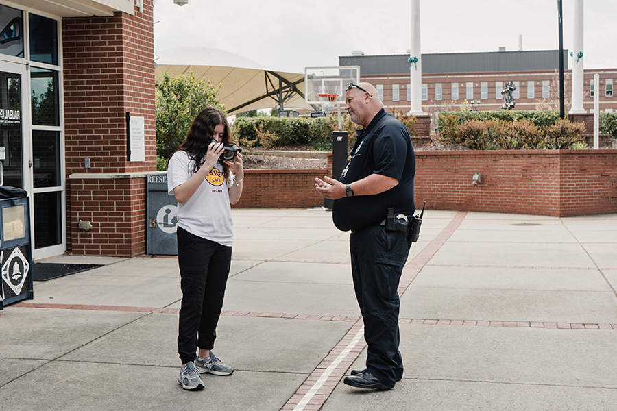 A police officer talks to a college student holding a special pair of goggles engineered to make the person wearing them feel the effects of being impaired by alcohol as part of an Arrive Alive Tour event.