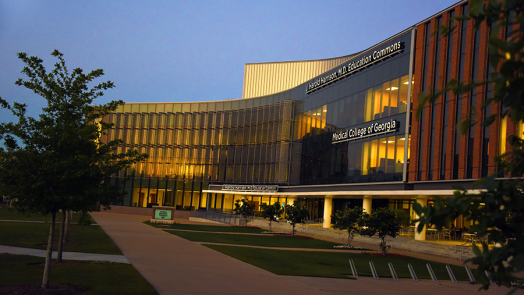 Sunset over a large, modern education building on a medical college campus.