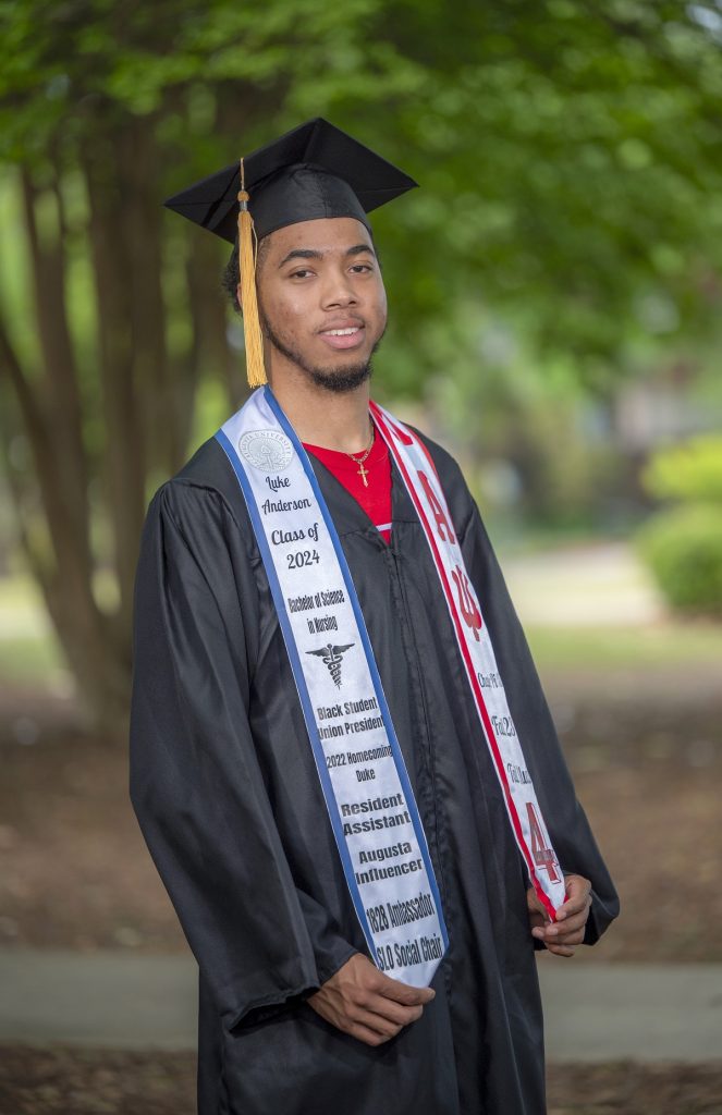 a man stands outside with his graduation cap, gown and stoll