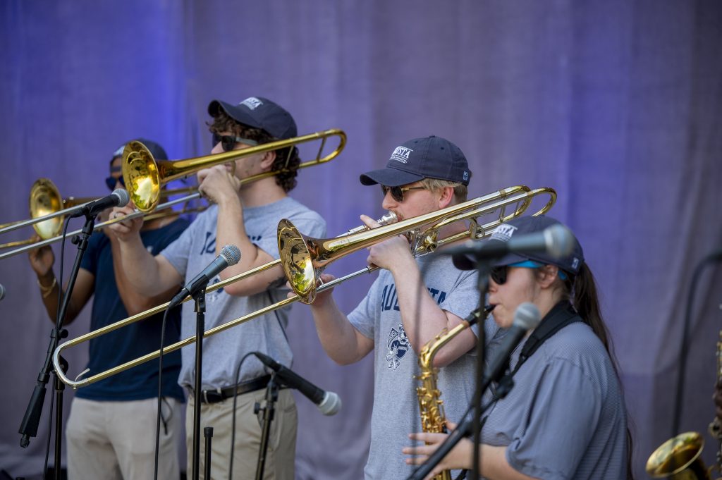 A group of students play trombones and saxophones.