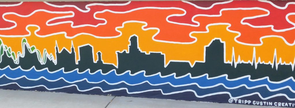 A mural shows a cityscape with waves in front.