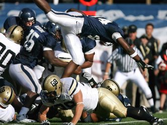 A football player leaps over a pile of players