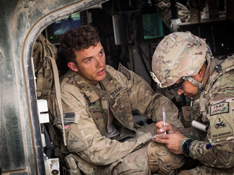 Soldier receives aid sitting in helicopter