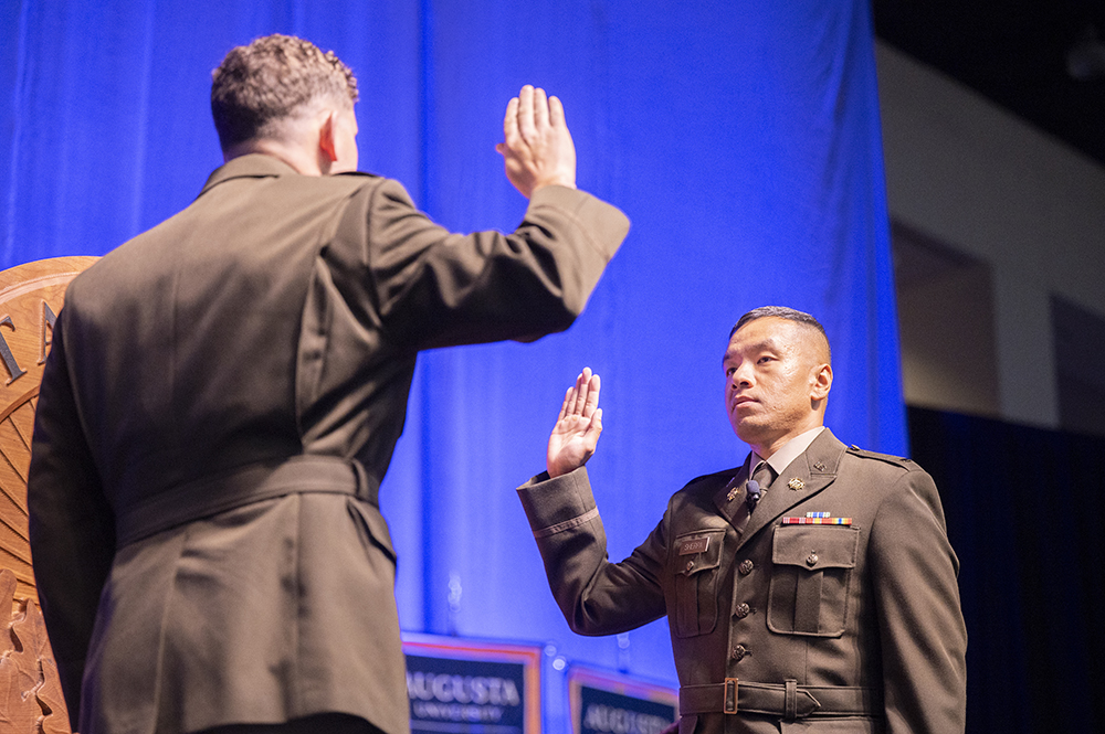 A soldier is sworn in while holding up his right hand.