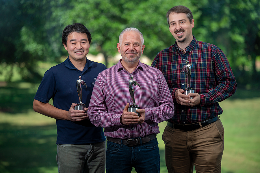 three men stand outside holding their silver Telly Awards