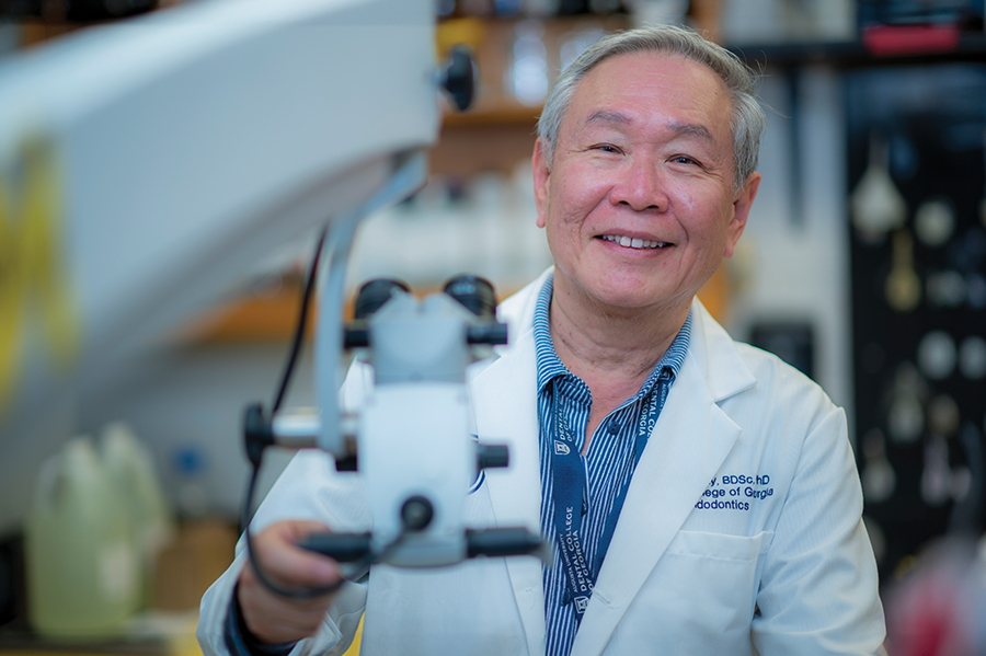 A male scientist stands in a lab while holding a piece of lab equipment.