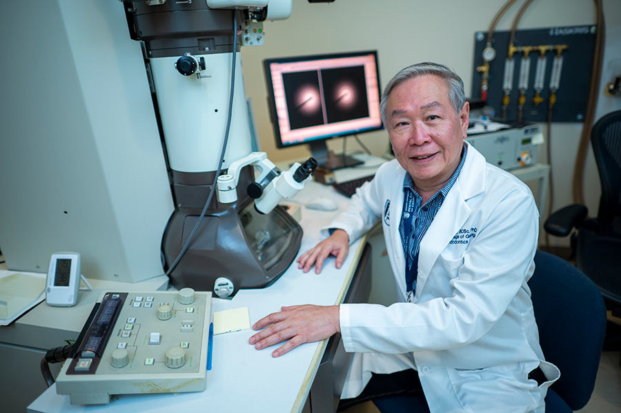 A male scientist sits at a table in a lab.