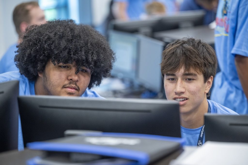 Two young men look at code on a computer screen