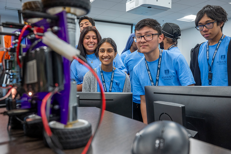 High school students gather around a computer to take a picture using the web camera.