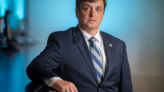 A man in a suit leans against a high counter top.