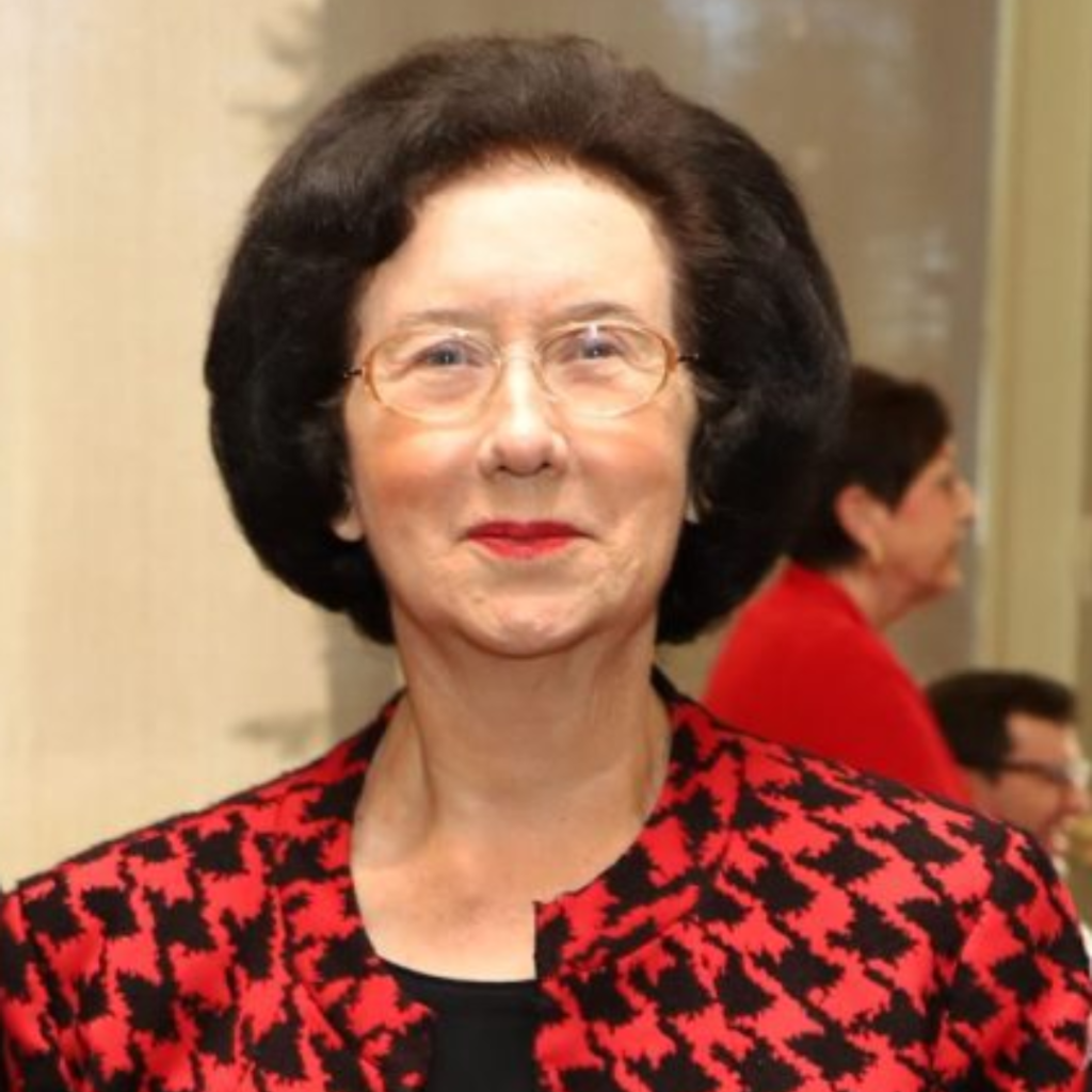 A woman in a black top and red and black jacket smiles at the camera