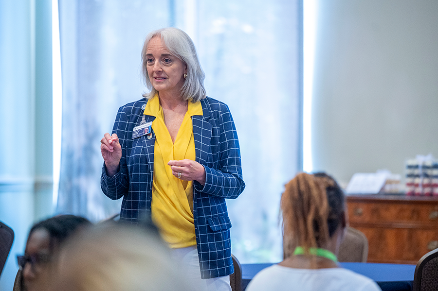 A college professor speaks to a room full of high school students.