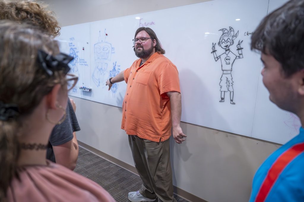 A teacher goes over white board sketches with students 