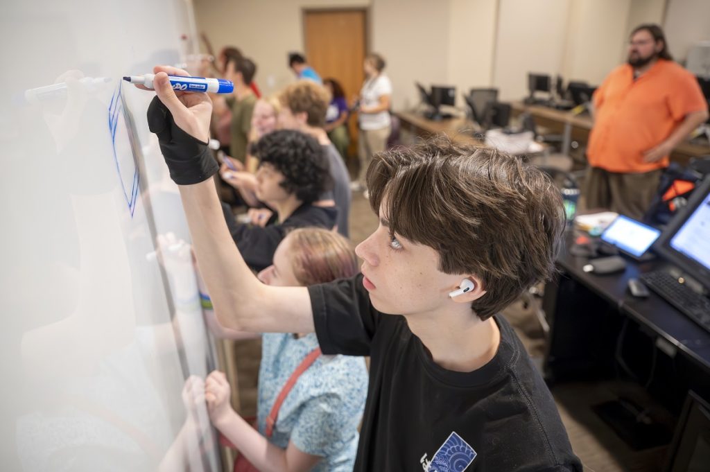 Students drawing on a white board during an animation camp