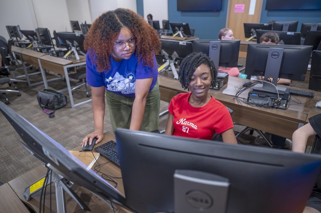 Two young ladies work on a computer