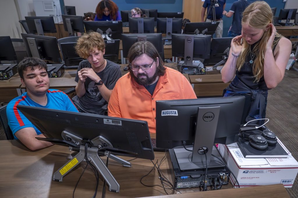 A professor works with students animating a short video on computers