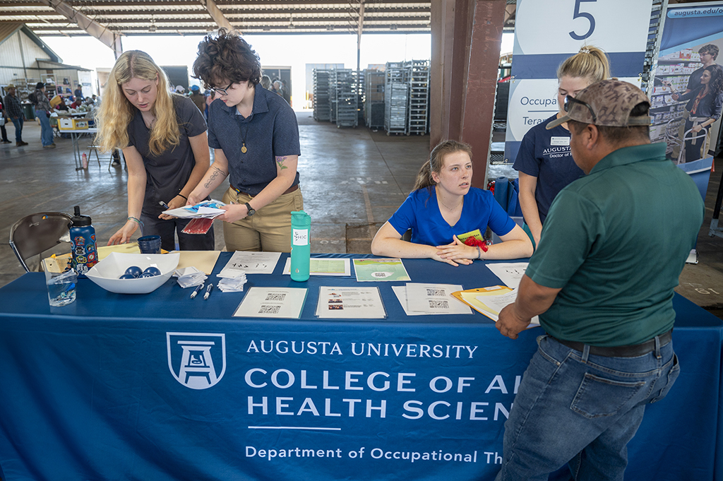 People standing at a table talking to a farm worker