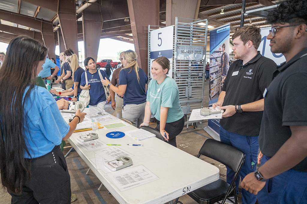 People standing at a table talking to a farm worker