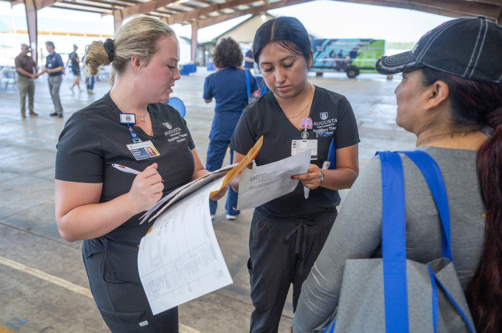 Two women talking and writing information down