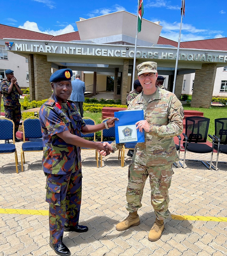 A Kenyan Defence Forces director hands a certificate and shakes the hand of a U.S. lieutenant colonel outside the Military Intelligence Corps Headquarters in Kenya.