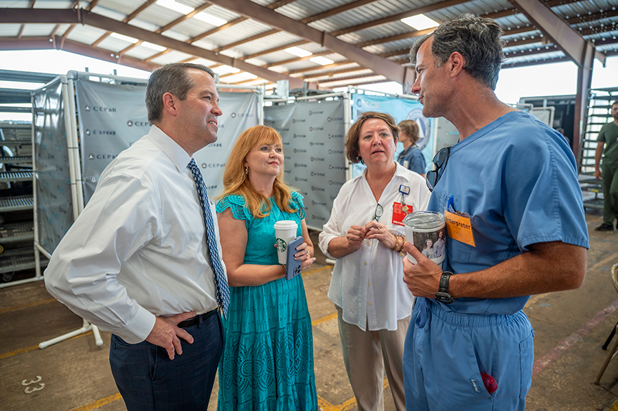 A man and a woman stand in a mobile clinic and talk with a physician and another woman.