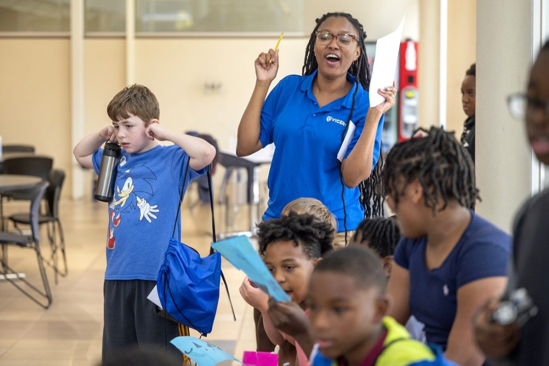 A VICEROY Summer Camp counselor cheers on as students watch the microbot competition