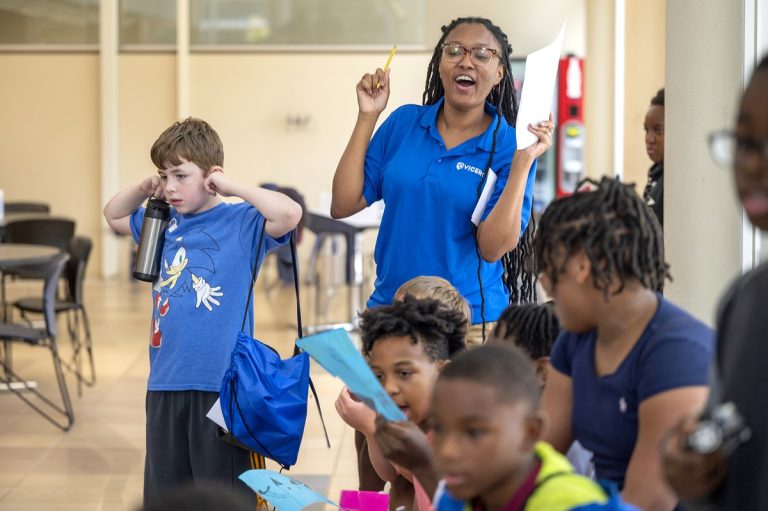 A VICEROY Summer Camp counselor cheers on as students watch the microbot competition