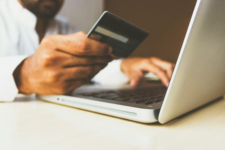 A person's hand with a credit card at a computer