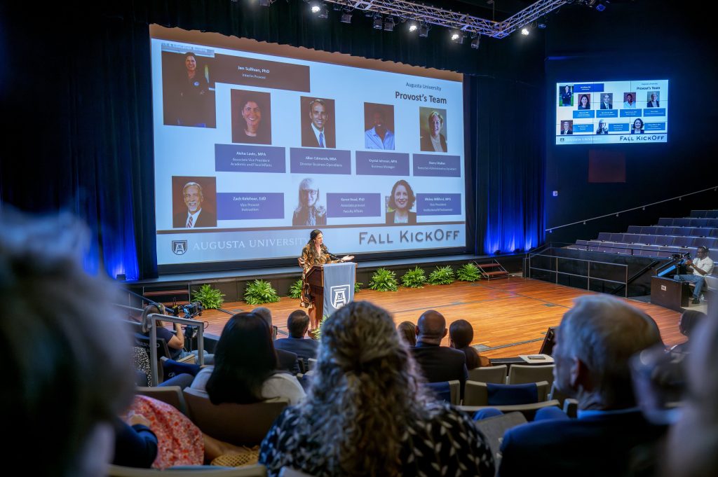 A woman delivers a presentation on a stage.