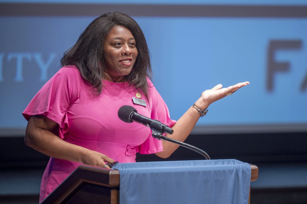 A woman delivers a presentation on a stage.