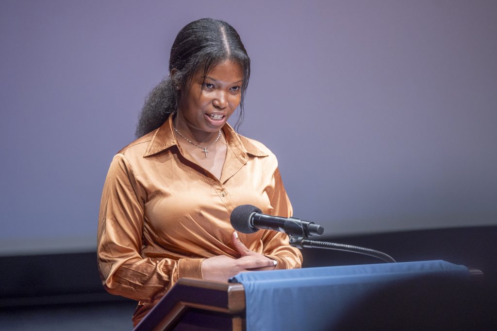 A woman delivers a presentation at a podium.