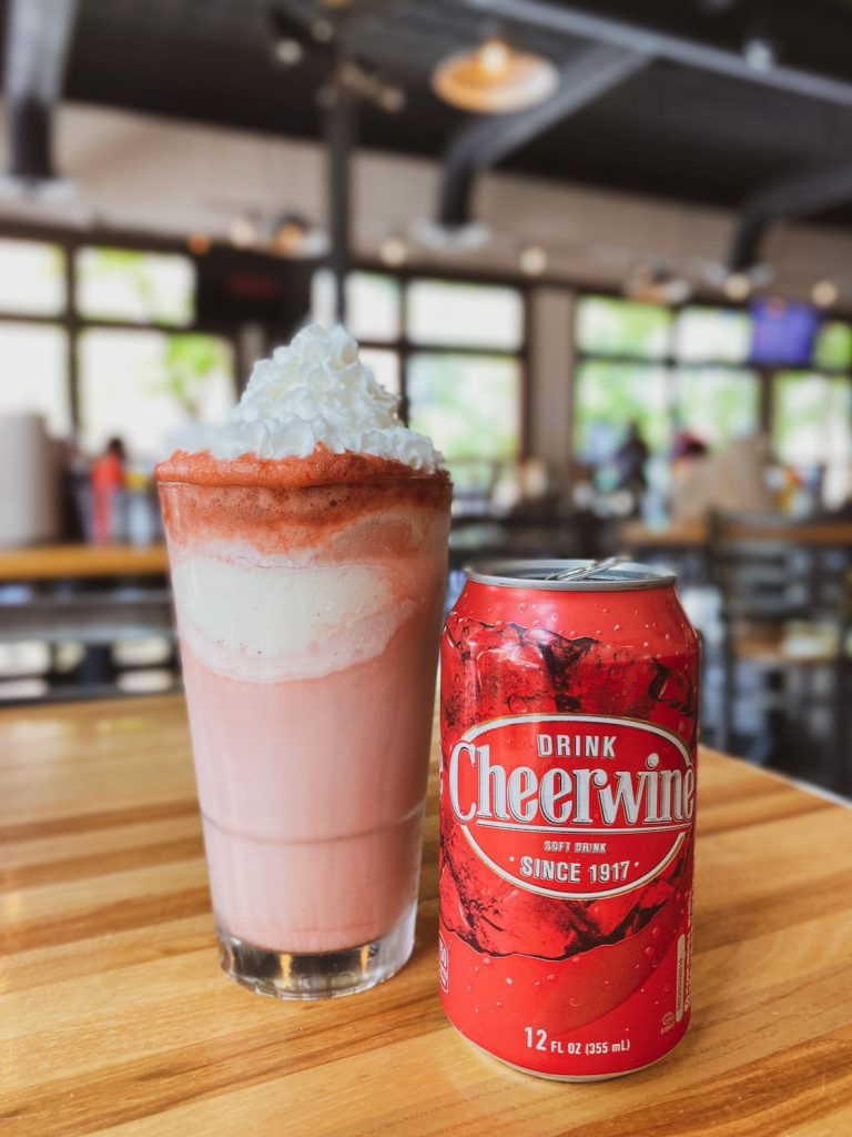 A milkshake with a can of Cheerwine next to it.