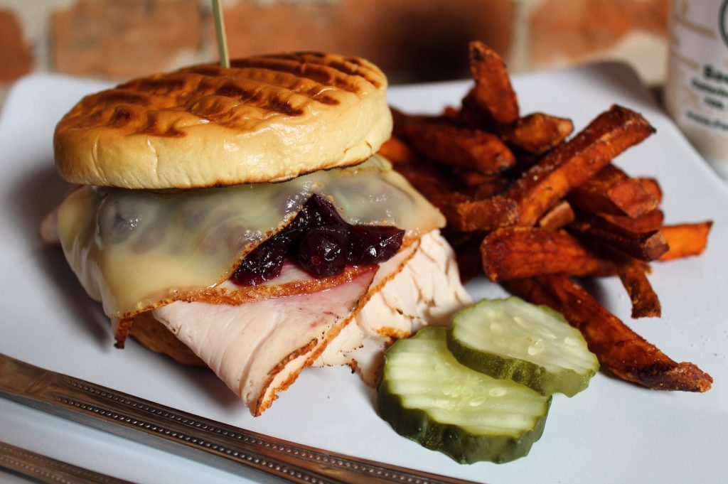 Turkey sandwich with a side of pickles and sweet potato fries.