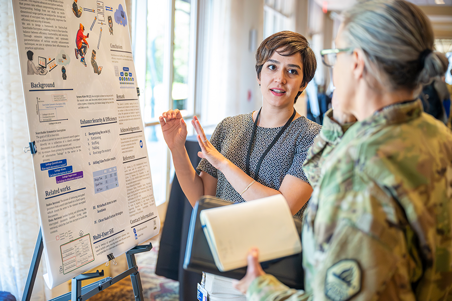 A woman speaks to a female soldier about information on a poster with research information.