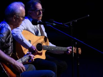 two men singing and playing guitar