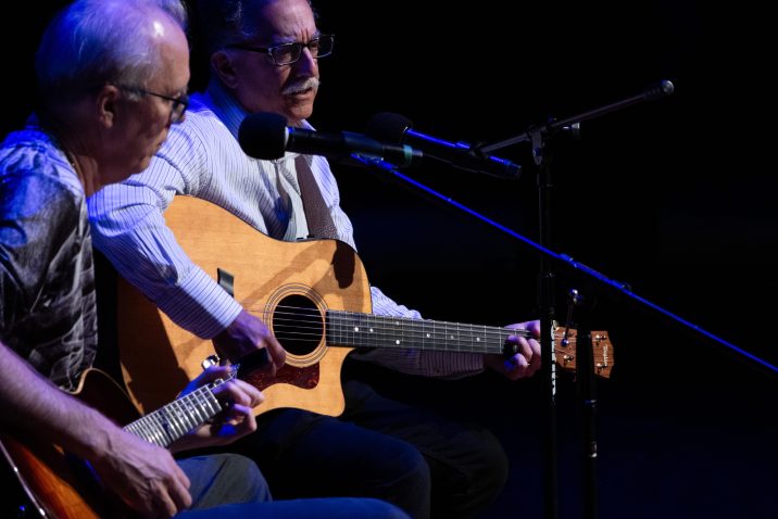 two men singing and playing guitar