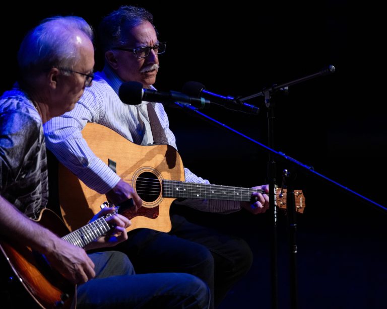 two men singing and playing guitar