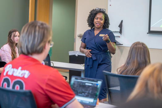 A professor teaching a room full of college students.