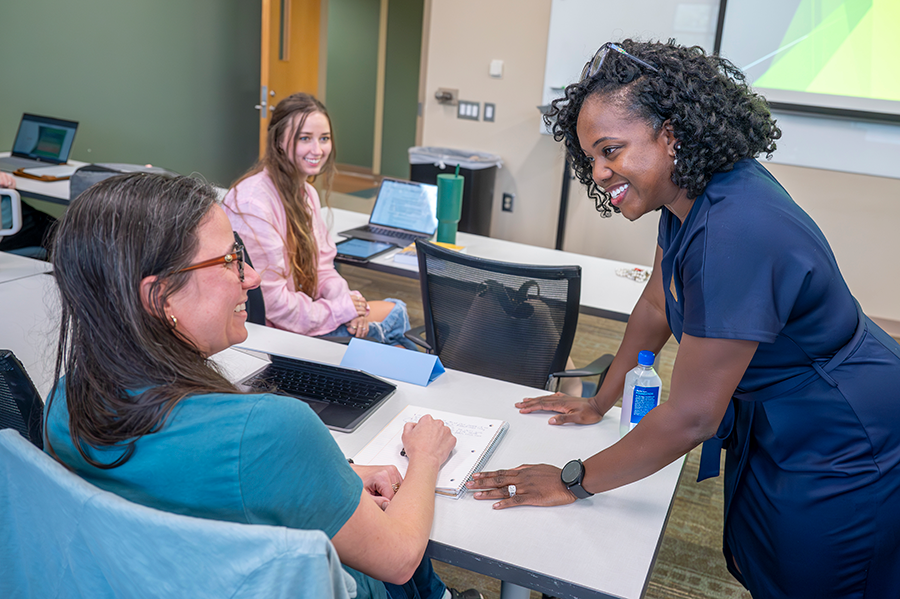 A college professor talks with a student in a classroom.