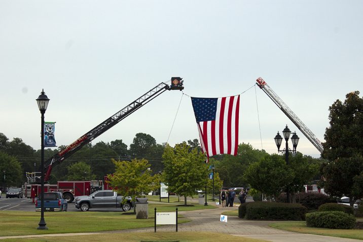 The American flag is raised by two cranes.